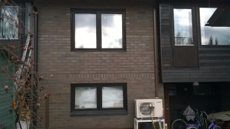 Ulkoyksikkö asennettuna tiilitalon seinälle, lunta maassa
